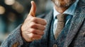 A man in a suit is giving a thumbs-up. This gesture expresses confidence and approval. The background is blurred Royalty Free Stock Photo