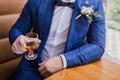 A man in a suit with a glass of cognac