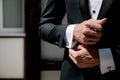 Man in suit with hand adjusts sleeve of shirt close-up. Close up of business buttoning up his shirt sleeves.