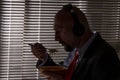 A man in a suit and headphones eats pasta against the background of a window with blinds. A special agent`s lunch at work, wiretap Royalty Free Stock Photo