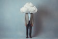 A man in a suit with his head in a cloud on a gray background. Depression, loneliness, mental health