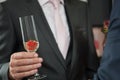 Man in suit holding a glas of sparkling wine or champagne and strawberry