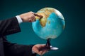 A man in suit holding globe and pointing at Africa continent. Business, education and travel concept