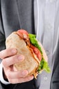 Man in suit holding to a BLT roll for lunch Royalty Free Stock Photo