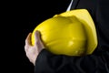 Man in a suit holding a yellow hardhat