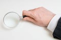 Man in suit holds magnifying glass. Isolated on white background