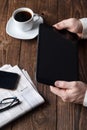 A man in a suit holds a tablet, a cup of coffee is standing nearby. Work outside the office, distance learning. Business Ideas. Royalty Free Stock Photo