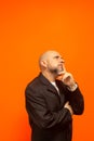 Man in suit jacket, bearded and bald looking up and making gestures