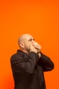 Man in suit jacket, bearded and bald looking up and making gestures