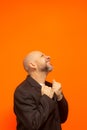 Man in suit jacket, bearded and bald looking up and making gestures
