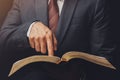 man in suit pointing a text on an open bible on a black background Royalty Free Stock Photo