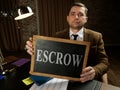 A man in a suit shows a sign escrow. Royalty Free Stock Photo