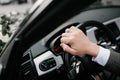 A man in a suit sits behind the wheel of a car