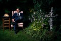 Man in Suit Sitting on Chair in Lush Garden