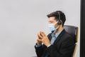 Man in suit sitting at a desk and clasp his hand, Young operator man with headset wear protection face mask Royalty Free Stock Photo