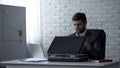 Man in suit sitting in office with open briefcase, preparing for business trip