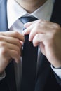 A man in a suit straightens his tie, close-up