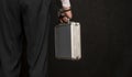 A man in a suit with a suitcase handcuffed on a black background, close-up, selective focus, dark tonality. Concept: secure delive