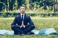 Man in a suit with tie. Business man relaxing in a park in the lotus position, he can`t relax in any way, meditation in the park Royalty Free Stock Photo