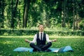 Man in a suit with tie. Business man relaxing in a park in the lotus position, he can`t relax in any way, meditation Royalty Free Stock Photo