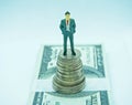 Man in a suit on top of a pile of coins in a white background Royalty Free Stock Photo