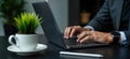 Man in suit types on laptop keyboard. Businessman works on modern computer in office. Focuses on project networking. Workplace
