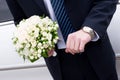 A man in suit with watch handsand a flower bouquet Royalty Free Stock Photo