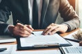 A man in a suit is writing on a piece paper with a pen Royalty Free Stock Photo