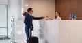 Man with suitcase in hotel check out at reception or front office Royalty Free Stock Photo