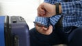 Man with Suitcase Waiting Transportation Checking Time on His Hand Watch and Text Using a Cellphone Royalty Free Stock Photo