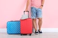 Man with suitcases near color wall.