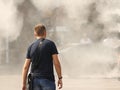 A man in summer clothes goes through the frame of a refreshing street shower. Use fine water dust during the hot season to refresh