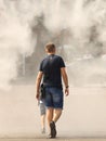 A man in summer clothes goes through the frame of a refreshing street shower. Use fine water dust during the hot season to refresh