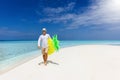 Man on summer holidays holding a yellow floaty walks down a beach