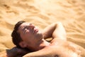 A man is sunbathing on the hot yellow sand. Beach holidays, a resort on the seashore. Sun protection, UV rays, sunscreen filter, Royalty Free Stock Photo