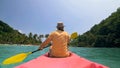 Man with sunglasses and hat rows pink plastic canoe along sea ag Royalty Free Stock Photo