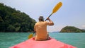 Man with sunglasses and hat rows pink plastic canoe along sea ag Royalty Free Stock Photo