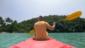 Man with sunglasses and hat rows pink plastic canoe along sea ag Royalty Free Stock Photo