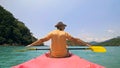 Man with sunglasses and hat rows pink plastic canoe along sea ag Royalty Free Stock Photo