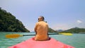 Man with sunglasses and hat rows pink plastic canoe along sea ag Royalty Free Stock Photo