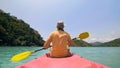 Man with sunglasses and hat rows pink plastic canoe along sea ag Royalty Free Stock Photo