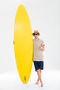 Man in sunglasses and hat showing thumbs up holding surfboard Royalty Free Stock Photo