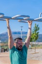 man with beard and sunglasses training his back by doing pull-ups on a bar in an outdoor gym Royalty Free Stock Photo