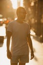 A man in sunglasses standing in the rays of the sunset on a street in Valencia