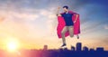 Man in superhero cape flying over sunset in city Royalty Free Stock Photo