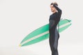 Man with surfboard shielding eyes at beach