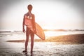 Man surfer carrying his surfboard at sunrise - Male silhouette in wetsuit waiting for the high waves on beach - Extreme sport Royalty Free Stock Photo