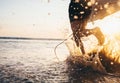 Man surfer run in ocean with surfboard. Closeup image water splashes and legs, sunset light Royalty Free Stock Photo