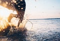 Man surfer run in ocean with surfboard. Closeup image water splashes and legs, sunset light Royalty Free Stock Photo