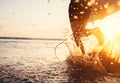 Man surfer run in ocean with surfboard. Closeup image water splashes and legs, sunset light Royalty Free Stock Photo